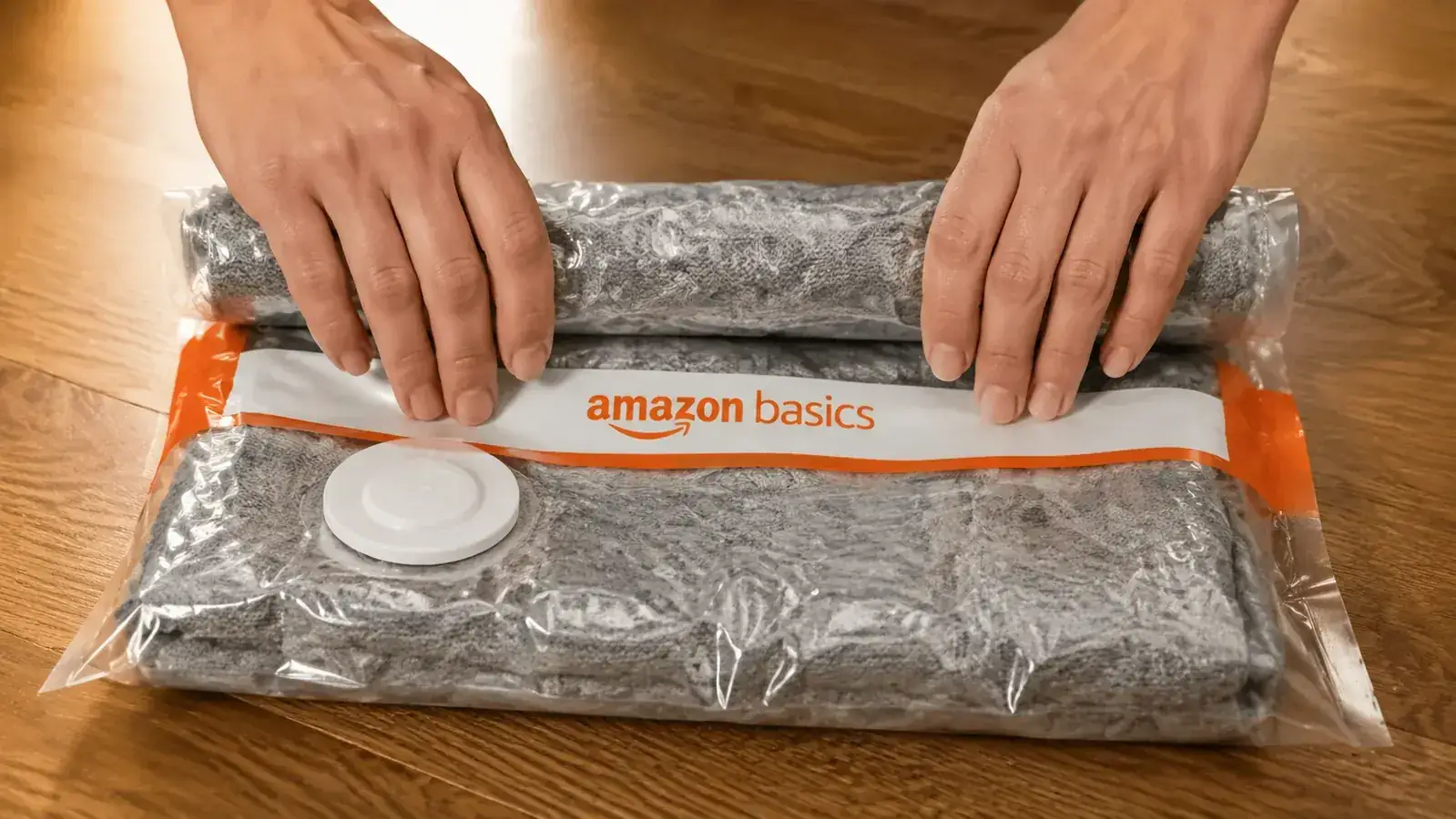 Hands pressing and rolling a vacuum storage bag on a flat surface to push air out before sealing